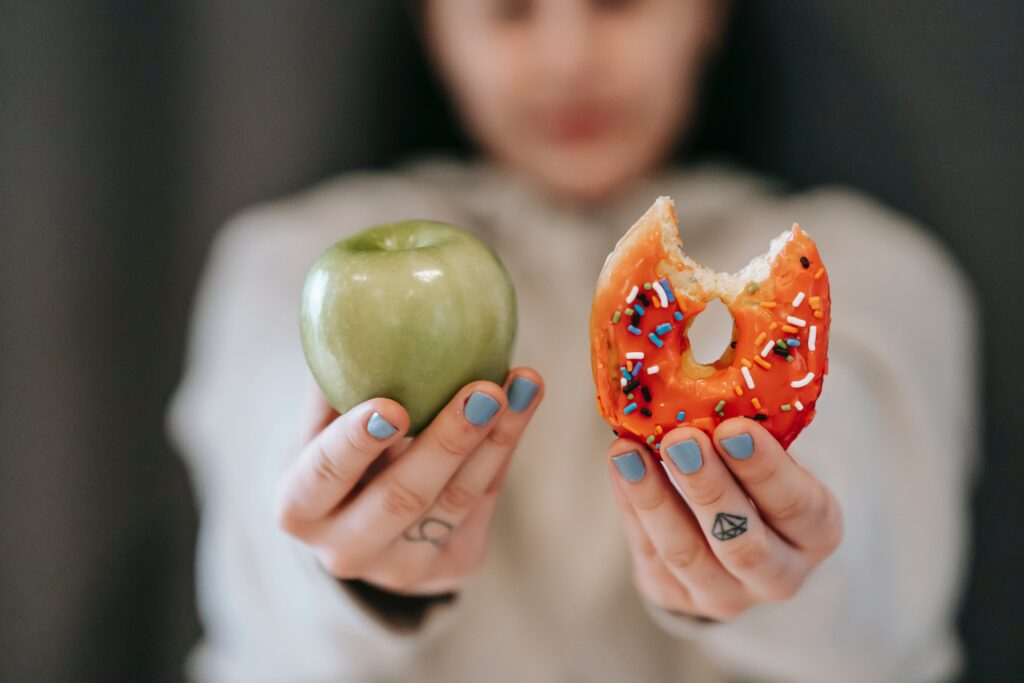 A person holding a donut and an apple