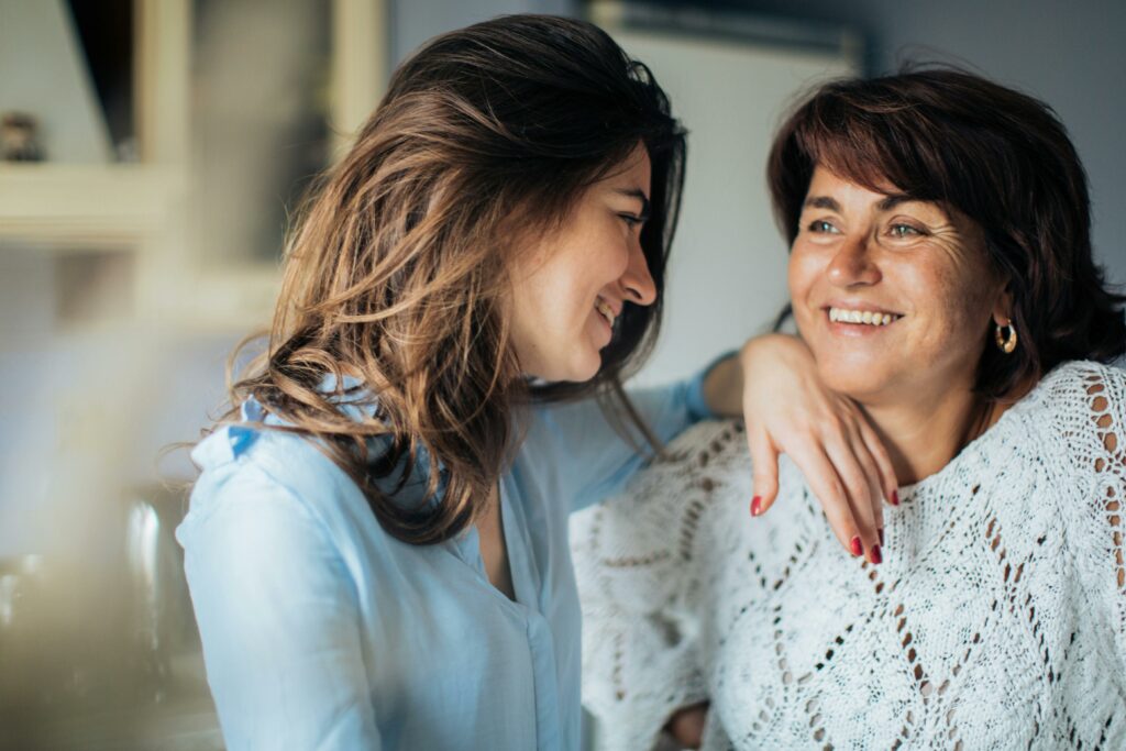 a smiling mother embraces her daughter with warmth and affection. They share a tender moment, expressing love and closeness through joyful expressions and body language